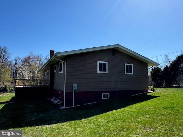 view of property exterior featuring a lawn, a wooden deck, and a chimney