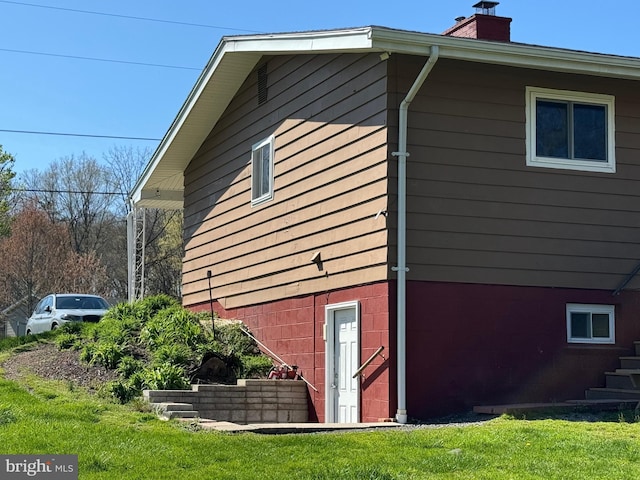 view of side of home featuring a chimney and a yard