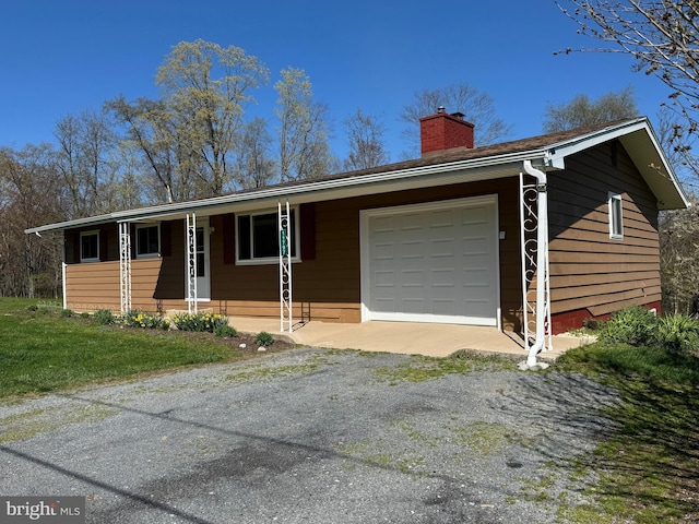 ranch-style house featuring an attached garage, aphalt driveway, and a chimney