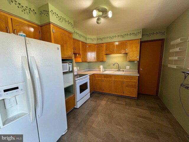kitchen with brown cabinetry, white appliances, light countertops, and a sink