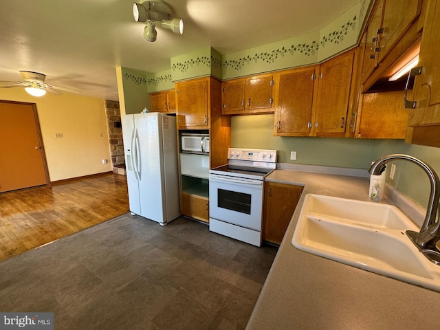 kitchen with brown cabinets, a sink, light countertops, white appliances, and a ceiling fan