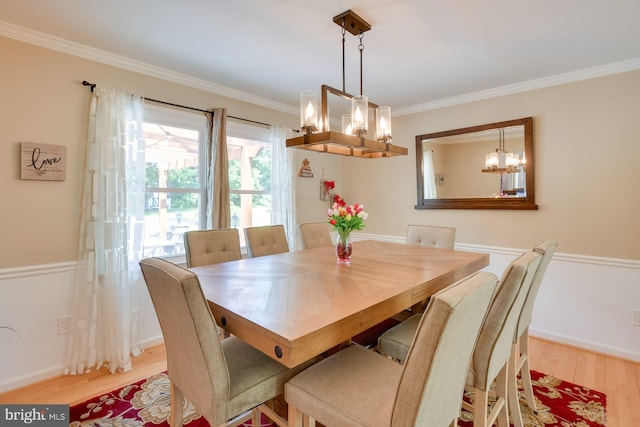 dining area featuring an inviting chandelier, ornamental molding, light wood-style floors, and baseboards