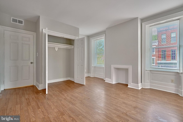 unfurnished bedroom featuring visible vents, multiple windows, and light wood-style floors