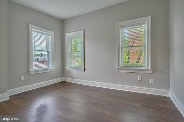 unfurnished room featuring plenty of natural light, baseboards, and dark wood-type flooring