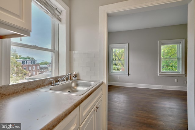 kitchen featuring baseboards, dark wood-style floors, light countertops, white cabinetry, and a sink