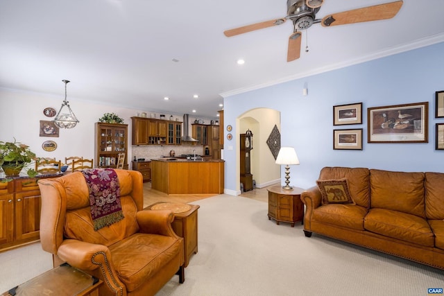 living area featuring a ceiling fan, light colored carpet, crown molding, arched walkways, and recessed lighting