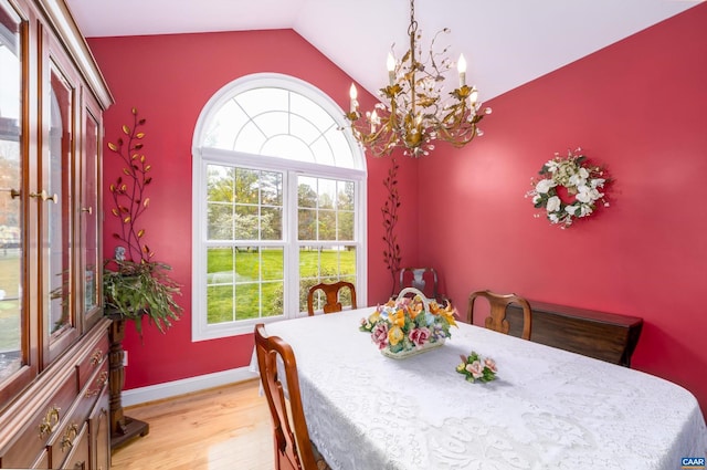 dining area featuring light wood-type flooring, baseboards, lofted ceiling, and a notable chandelier