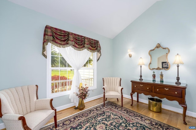 sitting room featuring baseboards, wood finished floors, and lofted ceiling