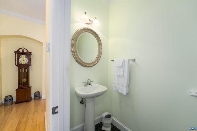 bathroom with baseboards, ornamental molding, and wood finished floors