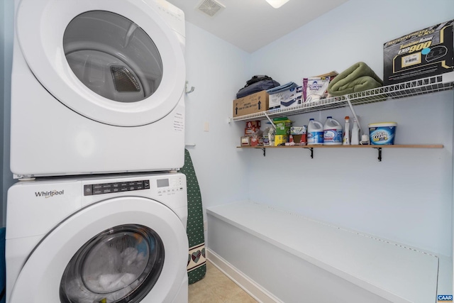 laundry area with laundry area, tile patterned floors, stacked washing maching and dryer, baseboards, and visible vents