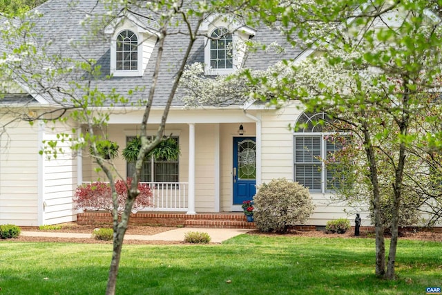 cape cod house with roof with shingles, covered porch, and a front yard