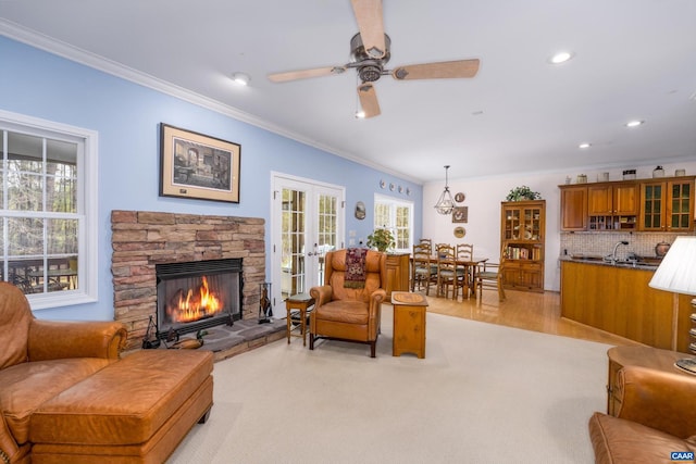 living room featuring ceiling fan, french doors, a stone fireplace, crown molding, and recessed lighting