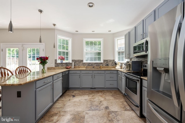 168 Sequester Dr, Stafford, VA 22556 - kitchen with stainless steel appliances, gray cabinets, a peninsula, light stone counters, and tasteful backsplash