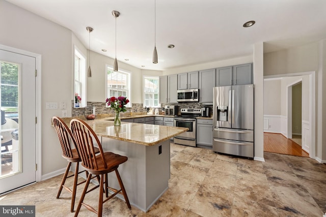 168 Sequester Dr, Stafford, VA 22556 - kitchen with appliances with stainless steel finishes, gray cabinets, a peninsula, light stone countertops, and decorative backsplash
