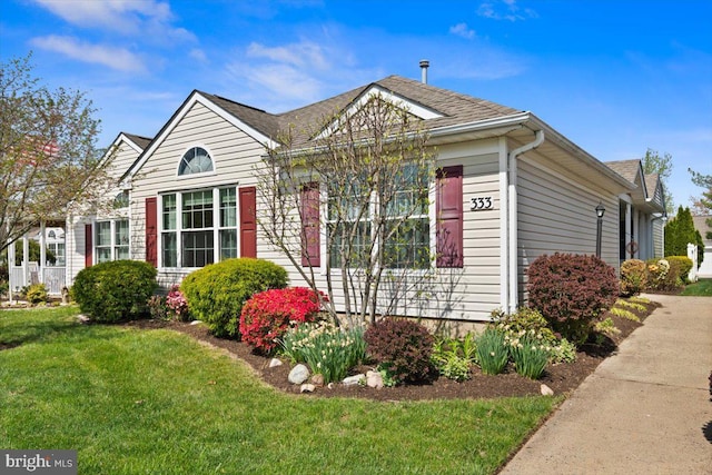 view of front facade with a shingled roof and a front yard