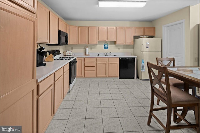 kitchen with light brown cabinetry, light countertops, a sink, light tile patterned floors, and black appliances