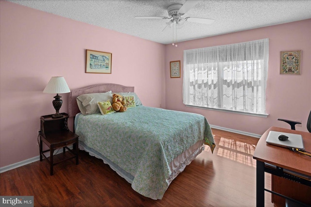 bedroom featuring ceiling fan, a textured ceiling, baseboards, and wood finished floors