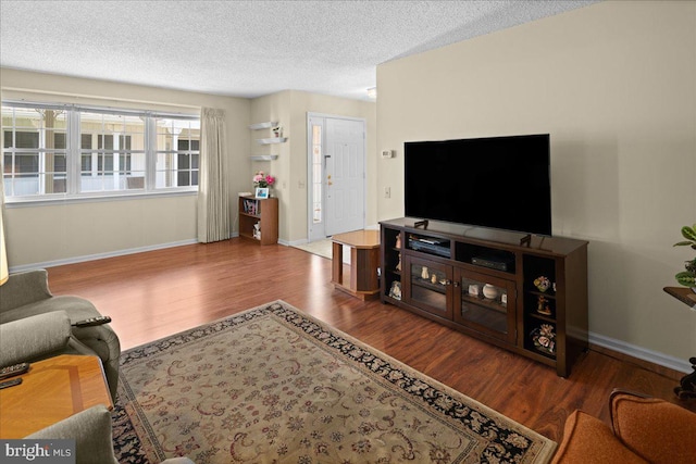 living area with a textured ceiling, baseboards, and wood finished floors