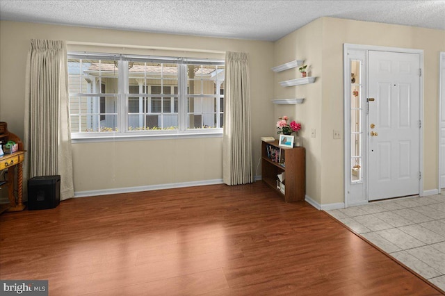 entryway with baseboards, a textured ceiling, and wood finished floors