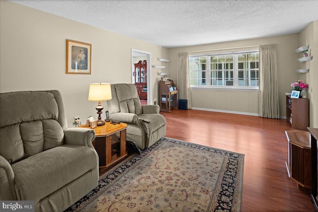 living room featuring baseboards, a textured ceiling, and wood finished floors