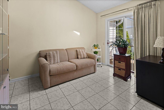 sitting room with baseboards, vaulted ceiling, and light tile patterned floors