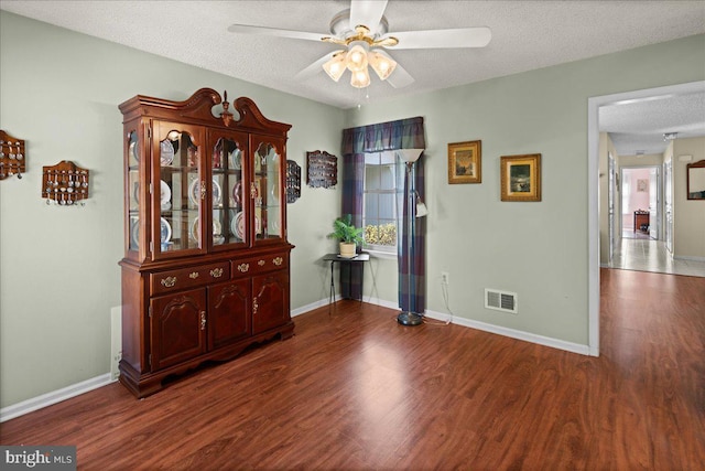 empty room featuring a textured ceiling, a ceiling fan, wood finished floors, and visible vents