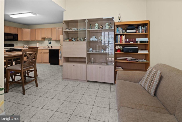 kitchen with light tile patterned flooring, light brown cabinets, light countertops, a sink, and black appliances