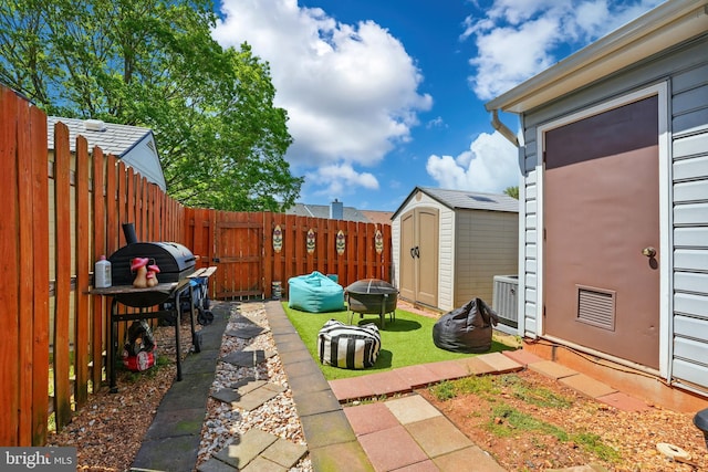 view of yard with a fenced backyard, a shed, and an outbuilding