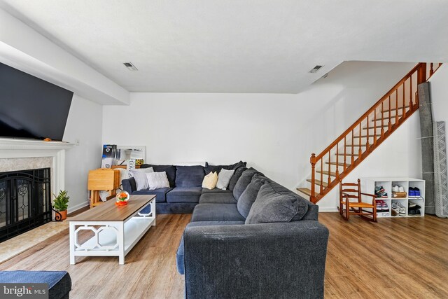 living room featuring visible vents, a high end fireplace, wood finished floors, and stairway