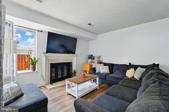 living area featuring visible vents, a high end fireplace, and wood finished floors