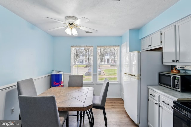 dining room with a ceiling fan, a textured ceiling, visible vents, and wood finished floors