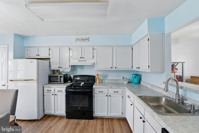 kitchen featuring electric range, a sink, light wood-style floors, freestanding refrigerator, and under cabinet range hood