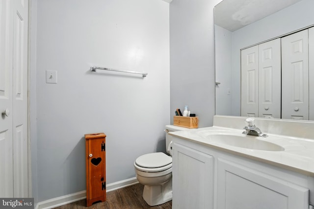 bathroom featuring vanity, a closet, wood finished floors, and toilet