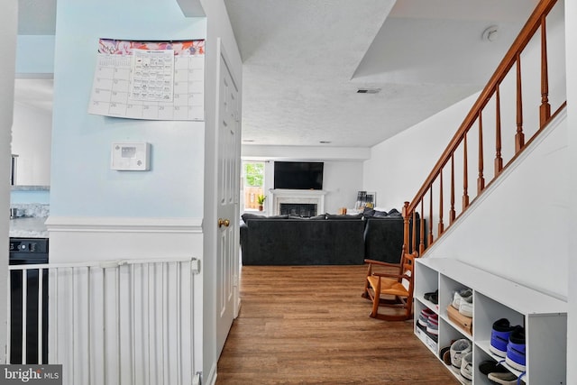 hallway with stairway, wood finished floors, and visible vents