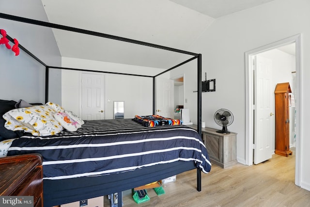 bedroom with baseboards, vaulted ceiling, and wood finished floors