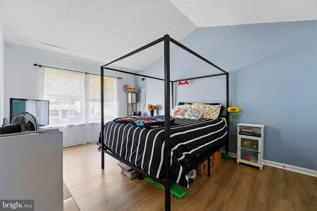 bedroom featuring baseboards, vaulted ceiling, and wood finished floors