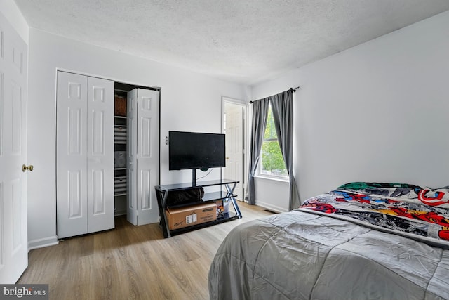 bedroom featuring baseboards, a textured ceiling, and wood finished floors