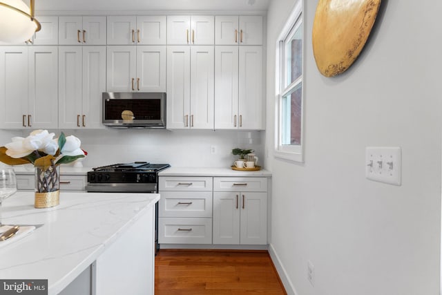 143 13th St NE, Washington, DC 20002 - kitchen with stainless steel microwave, wood finished floors, decorative backsplash, white cabinets, and light stone countertops