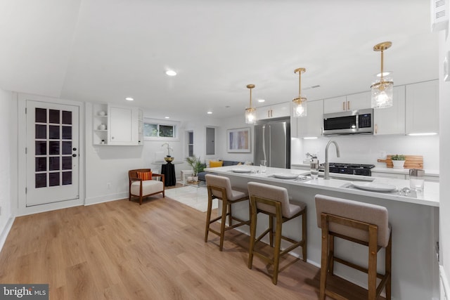 143 13th St NE, Washington, DC 20002 - kitchen with appliances with stainless steel finishes, white cabinetry, light wood-style floors, a breakfast bar, and pendant lighting