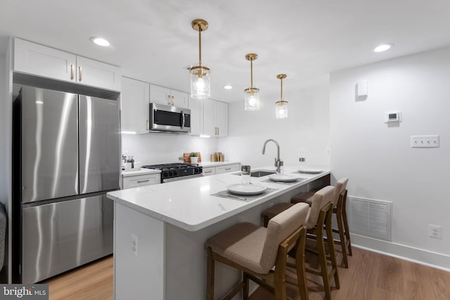 143 13th St NE, Washington, DC 20002 - kitchen with stainless steel appliances, a kitchen bar, white cabinetry, light wood-style floors, and recessed lighting