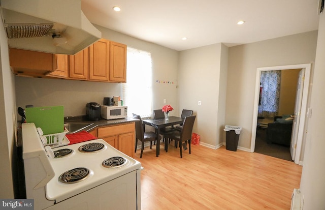 kitchen featuring a baseboard heating unit, light wood-style floors, white appliances, extractor fan, and dark countertops
