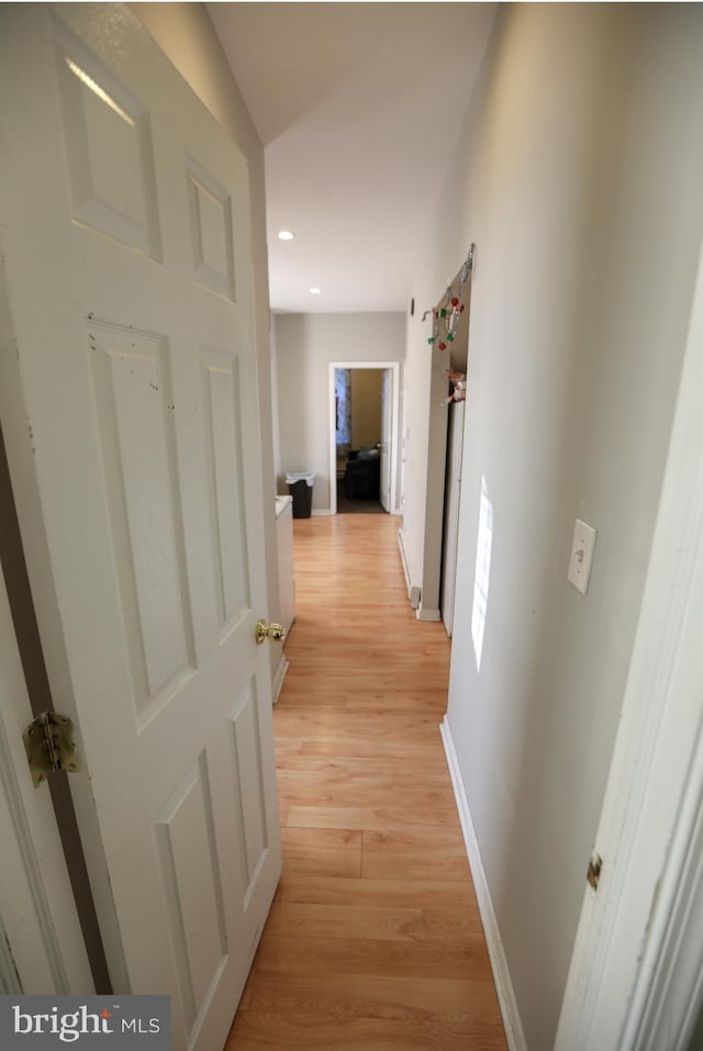 hall featuring baseboards, recessed lighting, and light wood-type flooring