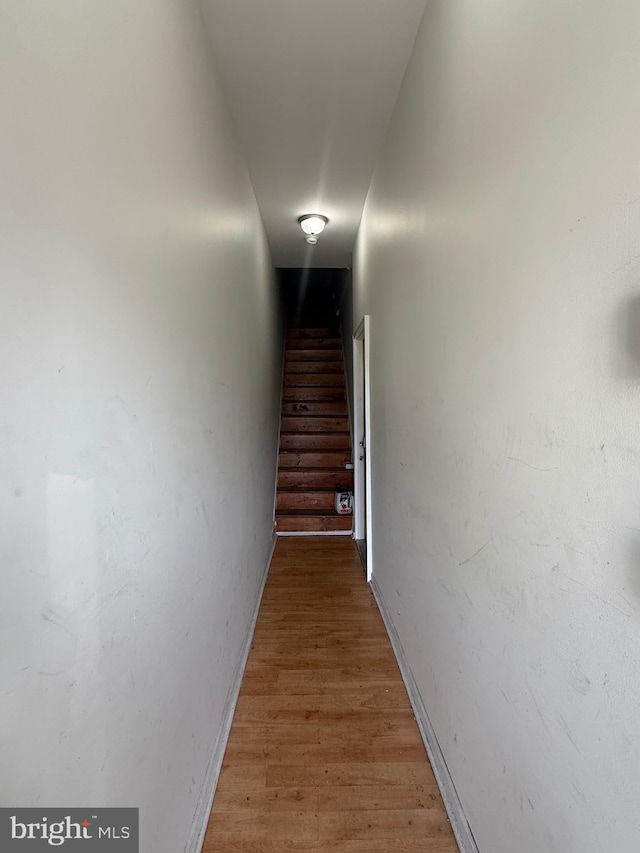 hall featuring baseboards, light wood-type flooring, and stairs