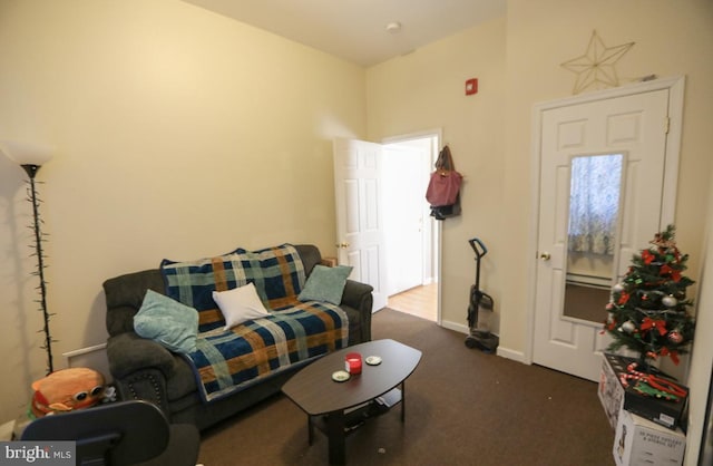 living area featuring dark colored carpet and baseboards