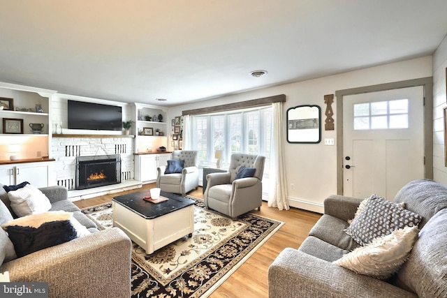 living room with light wood-style floors and a stone fireplace