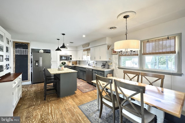 dining space with a notable chandelier, visible vents, and wood finished floors