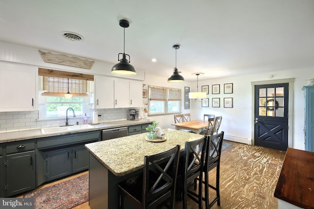 kitchen featuring a sink, decorative backsplash, baseboard heating, and wood finished floors