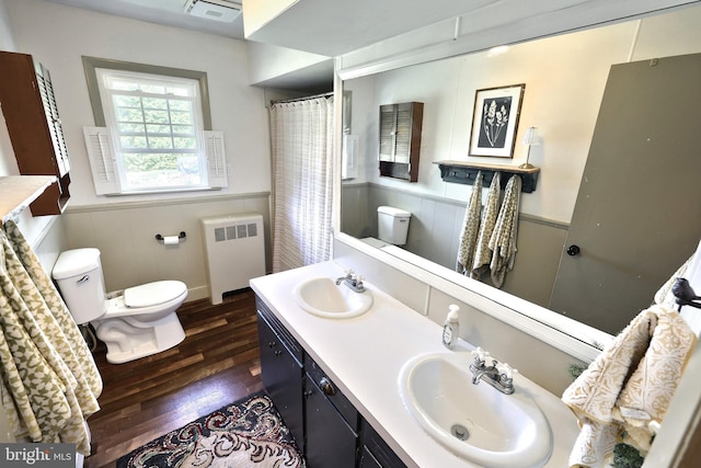 bathroom featuring wainscoting, a sink, wood-type flooring, toilet, and radiator