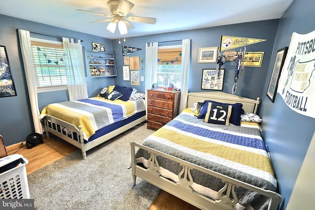 bedroom with ceiling fan, multiple windows, and wood finished floors