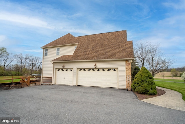 view of home's exterior with a garage, a shingled roof, and driveway